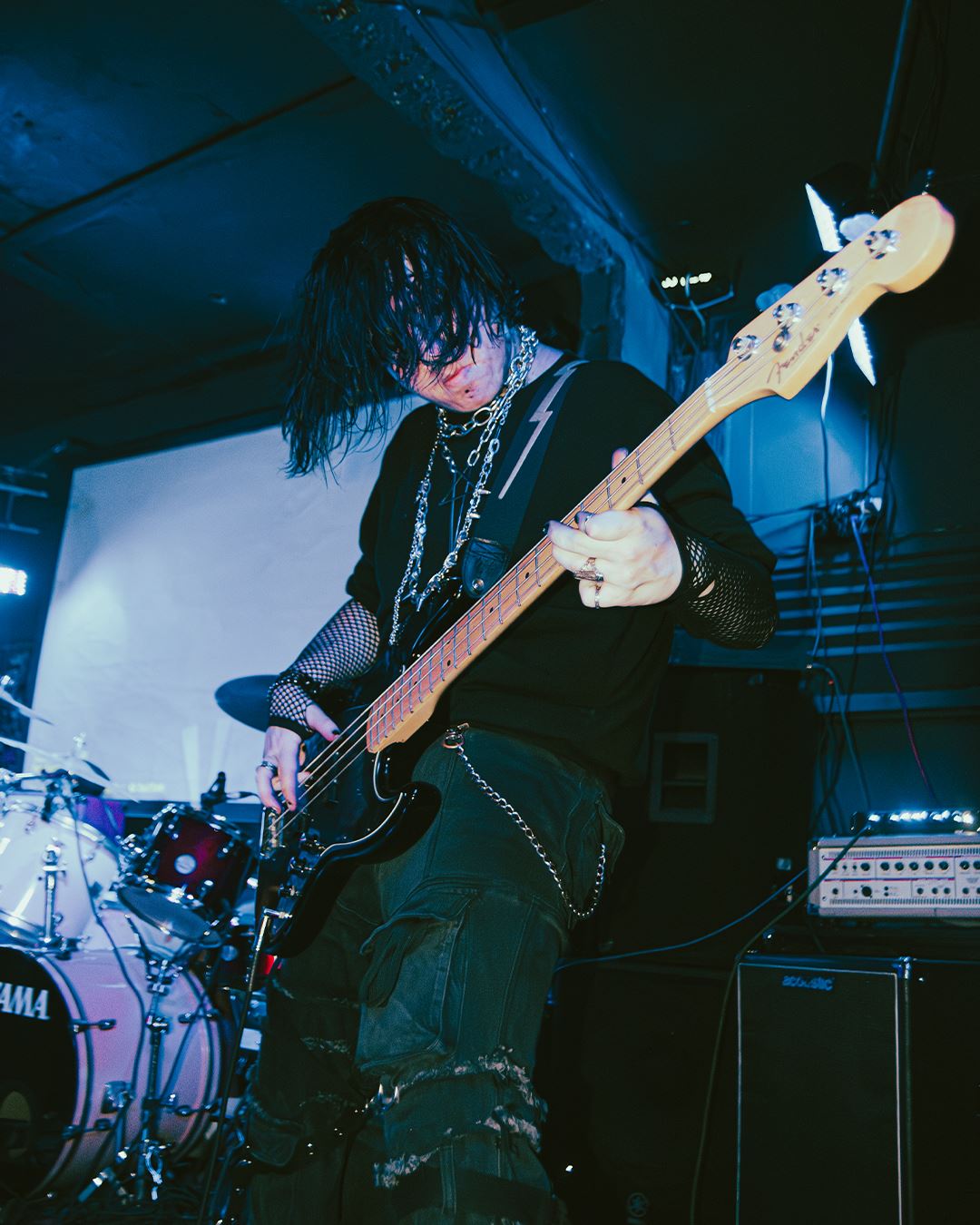 Bassist in black with chains, deep blue light