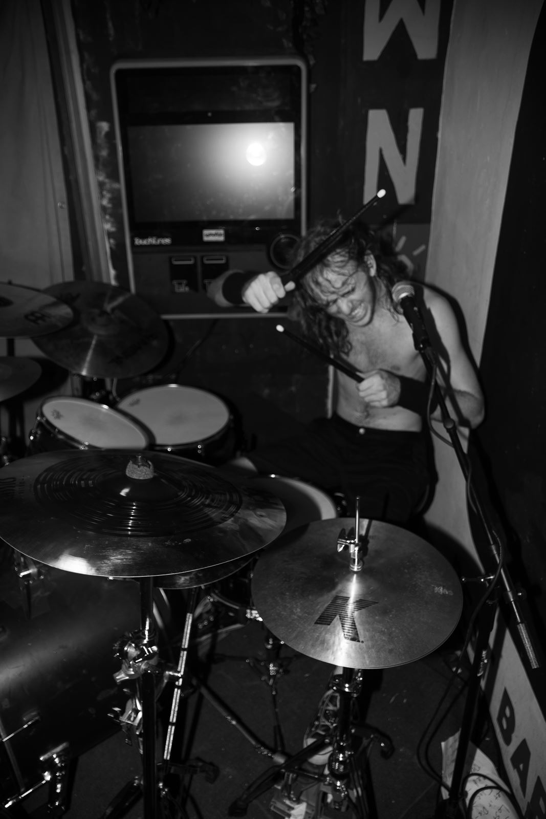 Shirtless drummer mid-hit, black and white