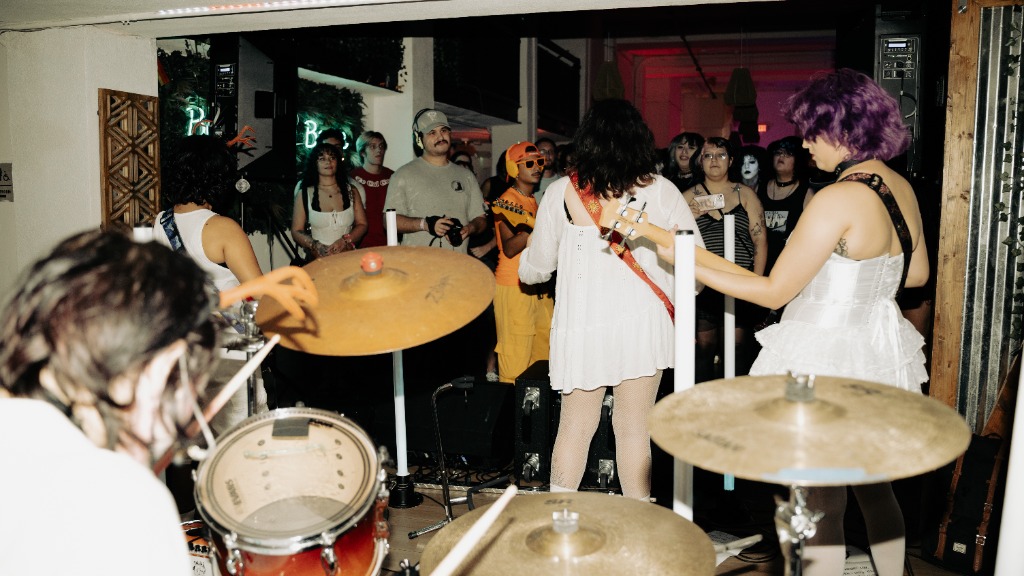 Band on stage from behind drummer looking at a crowd