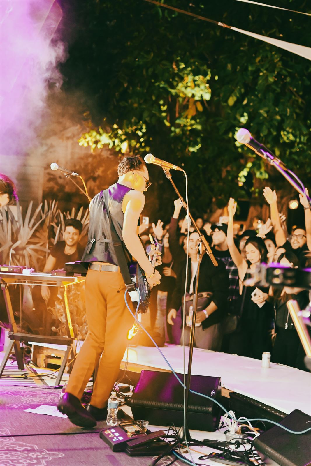 Performer facing an outdoor crowd through purple smoke