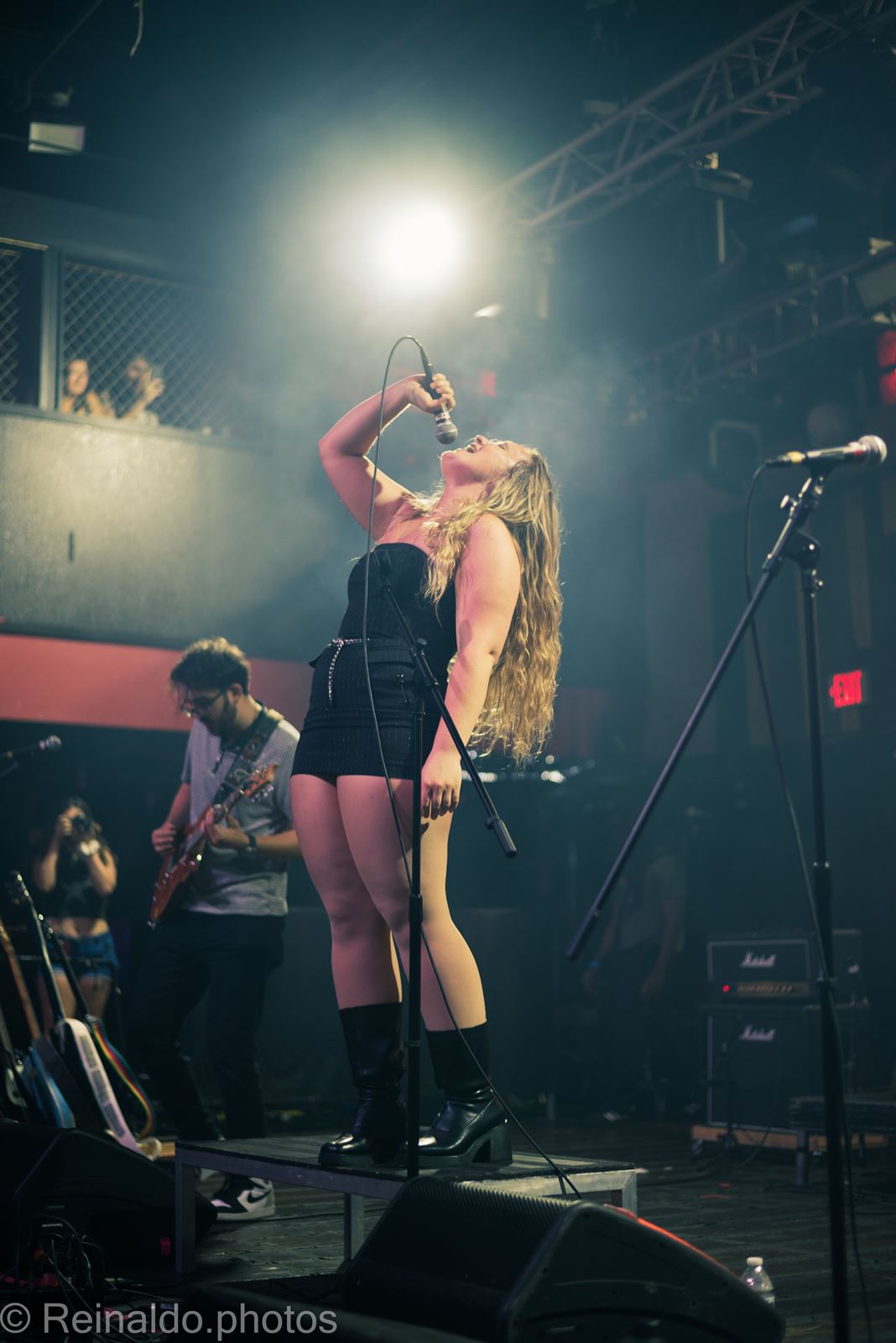Vocalist head back under a white spotlight